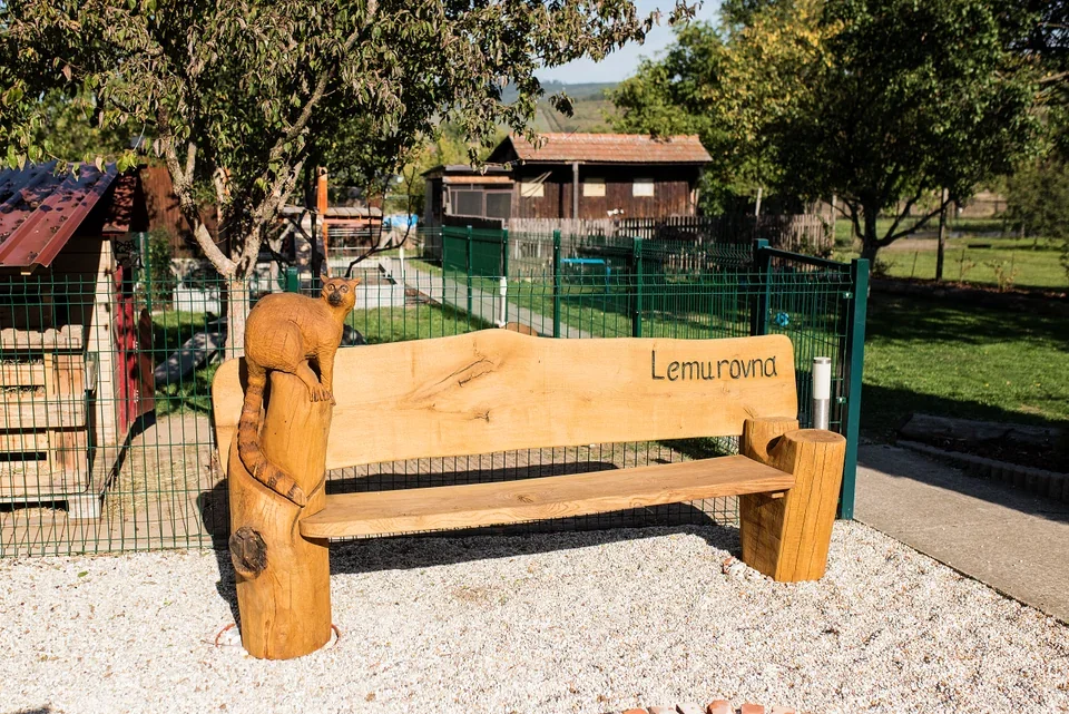 Dřevěná lavička se jménem Lemurovna u vstupu do areálu.